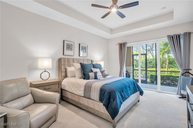 bedroom with light colored carpet, a tray ceiling, access to exterior, and ceiling fan