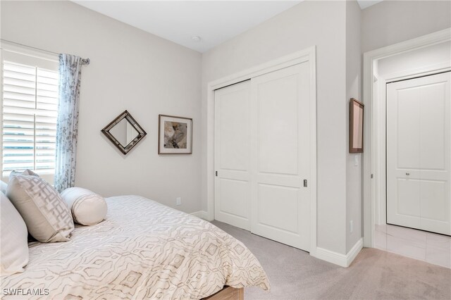 bedroom with light colored carpet, a closet, and multiple windows