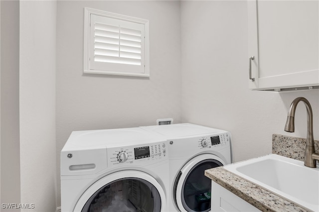 laundry room featuring washer and dryer, sink, and cabinets