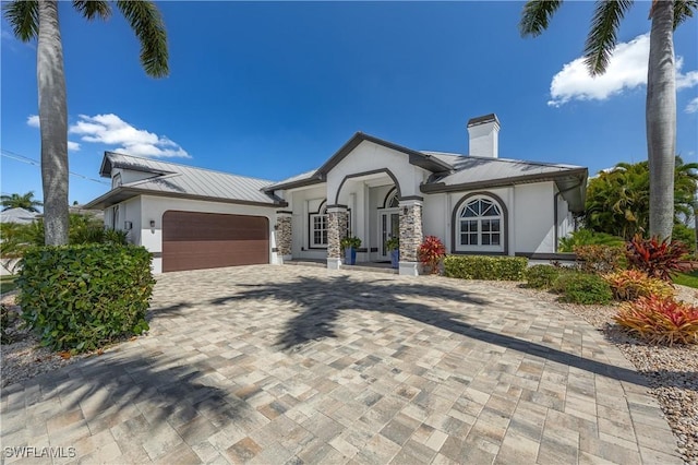 view of front of home featuring metal roof, decorative driveway, an attached garage, and stucco siding