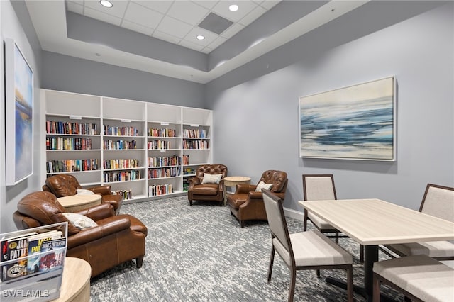 living area with carpet flooring, a paneled ceiling, and a raised ceiling