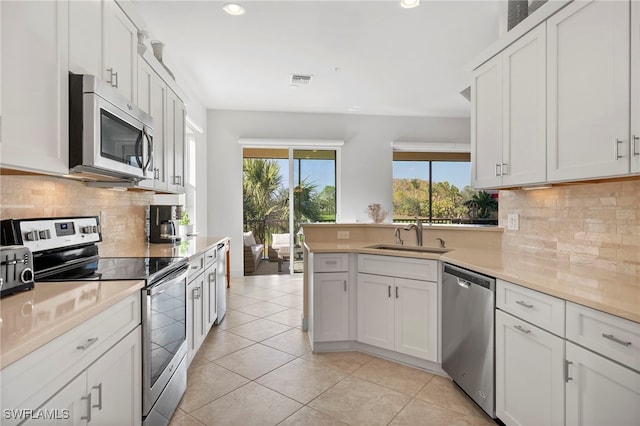 kitchen featuring white cabinetry, sink, stainless steel appliances, decorative backsplash, and light tile patterned flooring