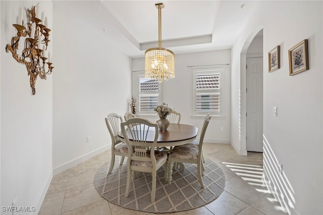 tiled dining space featuring a notable chandelier and a raised ceiling