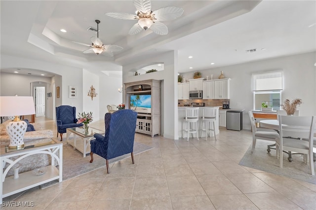 tiled living room featuring a raised ceiling and ceiling fan