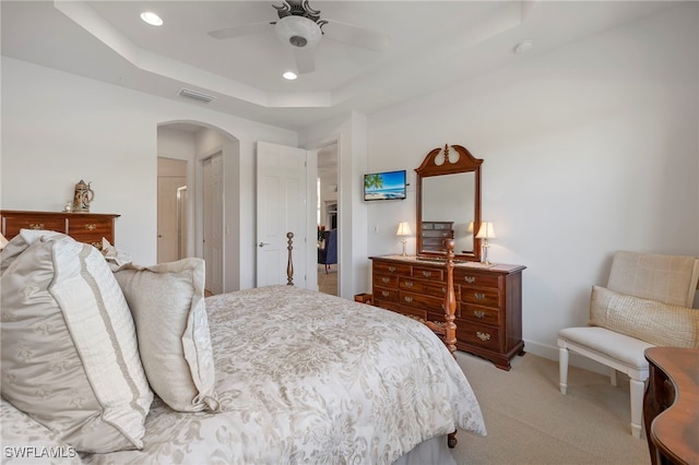 carpeted bedroom with a raised ceiling and ceiling fan