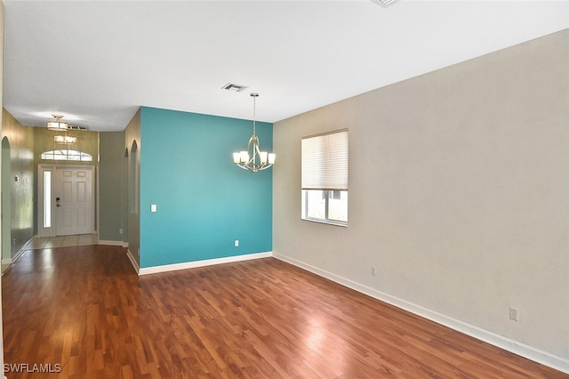 empty room featuring hardwood / wood-style flooring and a chandelier