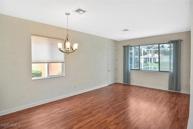 spare room with hardwood / wood-style floors and an inviting chandelier