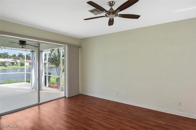 spare room featuring ceiling fan, a water view, and wood-type flooring