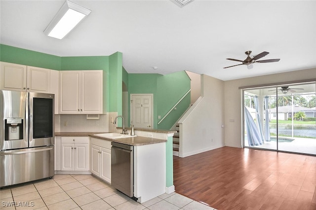 kitchen featuring ceiling fan, light wood-type flooring, appliances with stainless steel finishes, sink, and kitchen peninsula