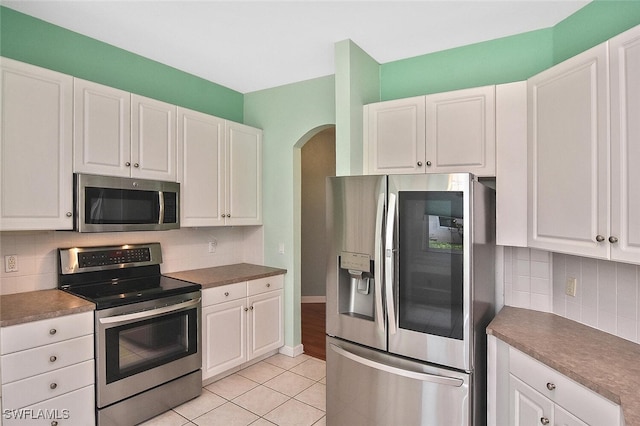 kitchen featuring light wood-type flooring, stainless steel appliances, tasteful backsplash, and white cabinets