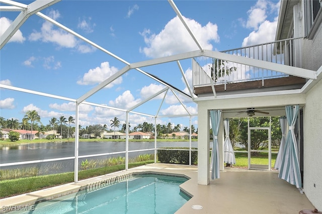 view of pool with glass enclosure, ceiling fan, and a water view