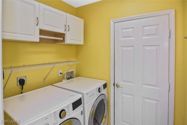 clothes washing area featuring washing machine and clothes dryer and cabinets