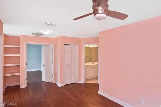 unfurnished bedroom featuring ceiling fan, a closet, ensuite bathroom, and dark wood-type flooring