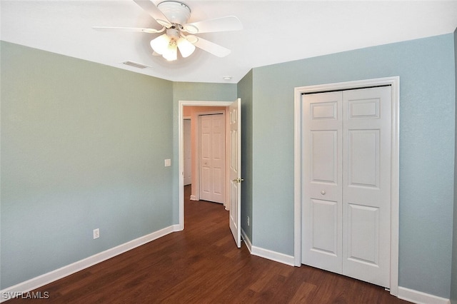 unfurnished bedroom featuring ceiling fan, a closet, and dark wood-type flooring