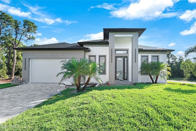 prairie-style house featuring a garage, decorative driveway, a front yard, and stucco siding