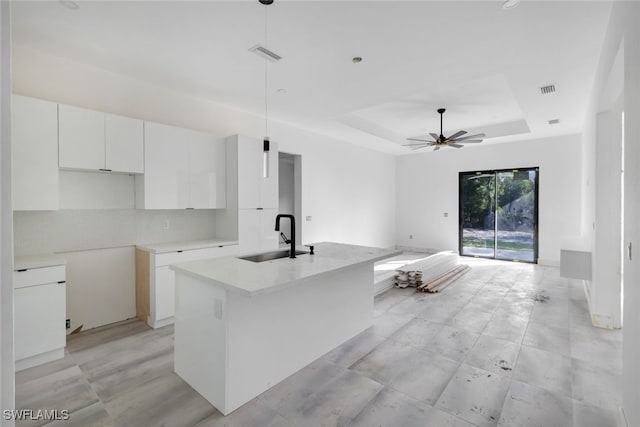 kitchen with white cabinets, an island with sink, hanging light fixtures, and sink