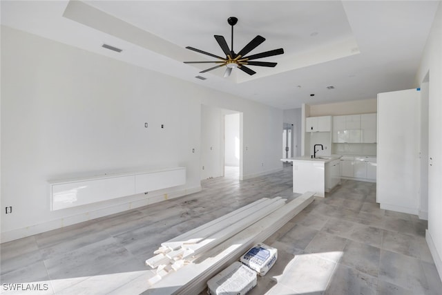 interior space featuring ceiling fan, a raised ceiling, and sink