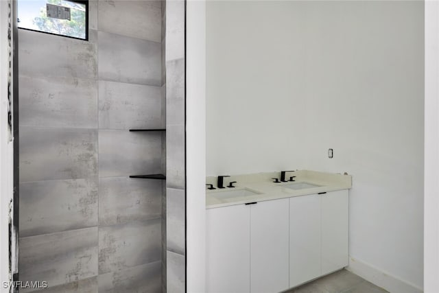 bathroom with a tile shower and vanity