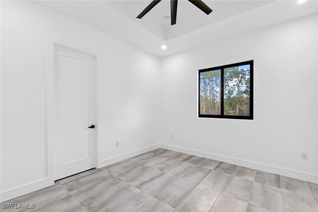 spare room with ceiling fan, baseboards, a tray ceiling, and recessed lighting