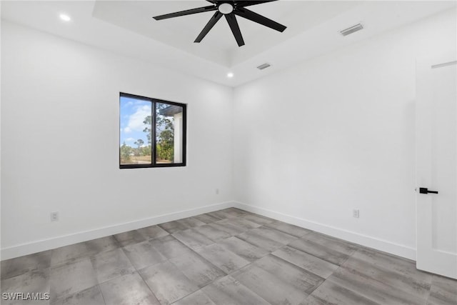 empty room with baseboards, visible vents, and a raised ceiling