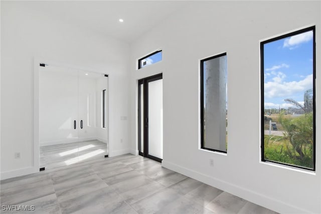 unfurnished room with recessed lighting, a high ceiling, and baseboards