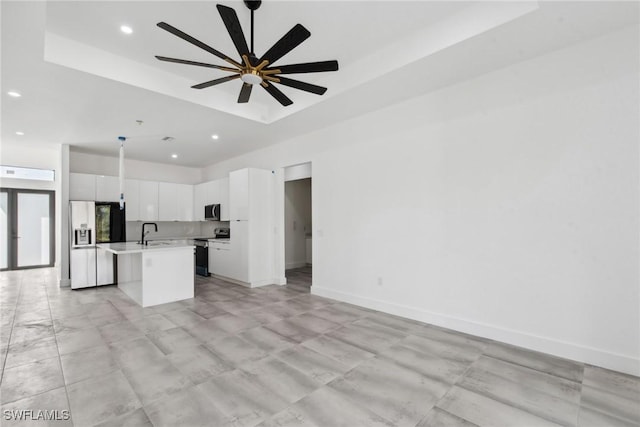 kitchen featuring a kitchen island with sink, stainless steel appliances, baseboards, open floor plan, and light countertops