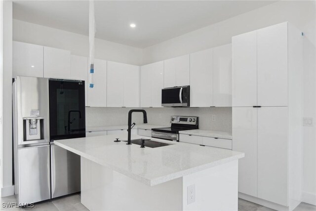 kitchen with a kitchen island with sink, stainless steel appliances, a sink, white cabinets, and modern cabinets