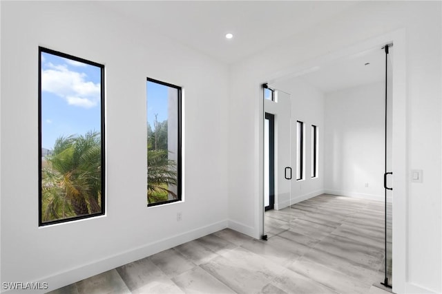 spare room with recessed lighting, plenty of natural light, and baseboards