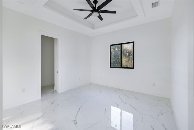 unfurnished room with ceiling fan and a raised ceiling