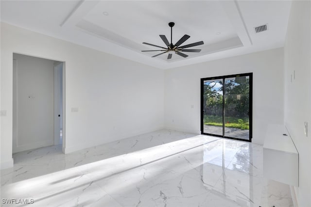 unfurnished room with ceiling fan and a tray ceiling