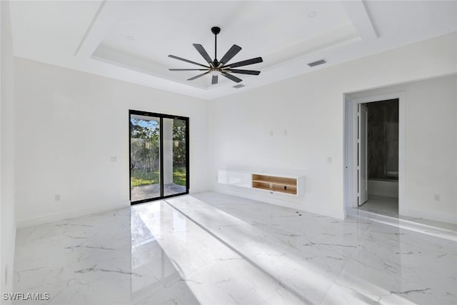 unfurnished living room with ceiling fan and a raised ceiling