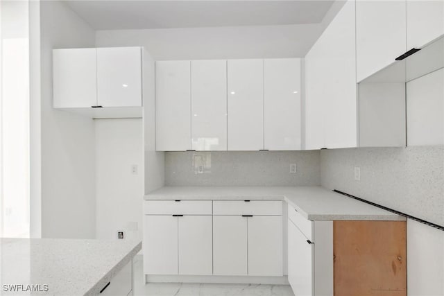 kitchen with modern cabinets, white cabinetry, light countertops, and decorative backsplash