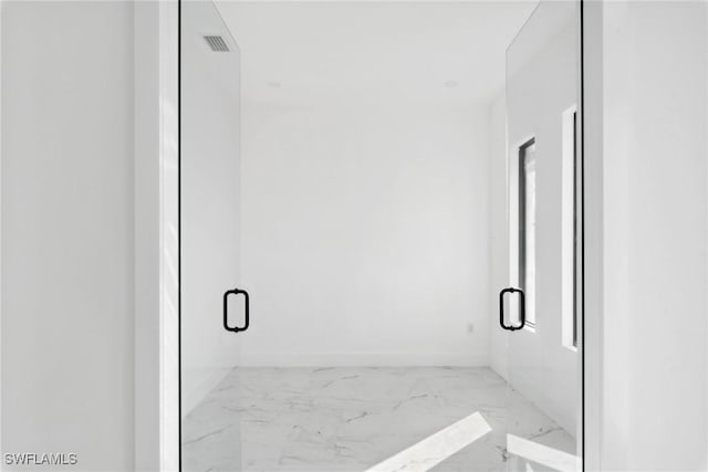 bathroom with marble finish floor, visible vents, a shower stall, and baseboards