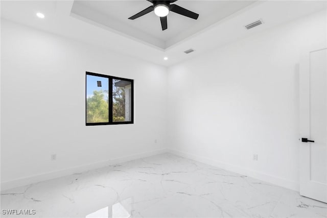 empty room with recessed lighting, visible vents, baseboards, marble finish floor, and a tray ceiling