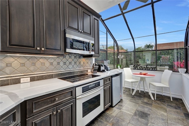 kitchen with a wealth of natural light, stainless steel appliances, backsplash, and dark brown cabinets