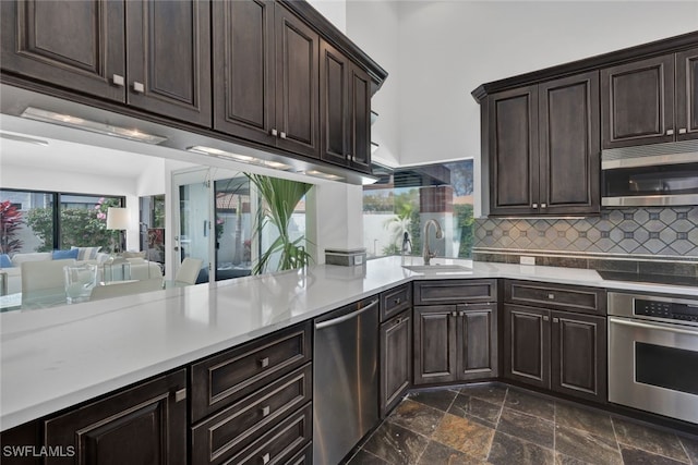 kitchen with appliances with stainless steel finishes, sink, decorative backsplash, and dark brown cabinetry