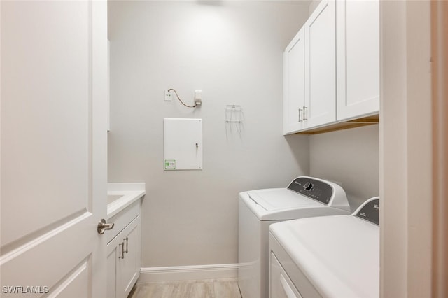 clothes washing area with cabinets and independent washer and dryer