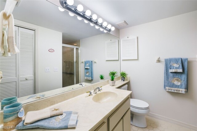 bathroom with vanity, a shower with shower door, tile patterned floors, and toilet