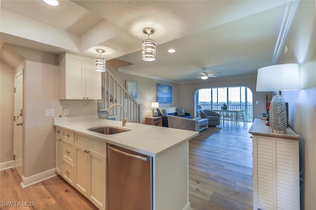 kitchen with light hardwood / wood-style floors, white cabinetry, stainless steel dishwasher, sink, and light stone counters