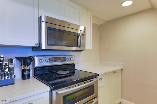 kitchen with white cabinets, light stone counters, and stainless steel appliances