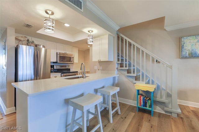 kitchen featuring light wood-type flooring, appliances with stainless steel finishes, sink, and kitchen peninsula