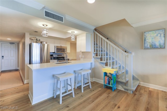 kitchen featuring kitchen peninsula, white cabinetry, light hardwood / wood-style floors, and stainless steel appliances