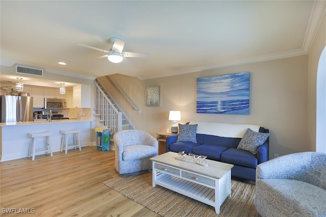 living room featuring light hardwood / wood-style flooring, ceiling fan, and crown molding