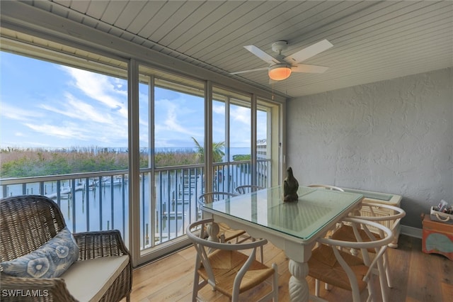 sunroom / solarium featuring ceiling fan and a water view