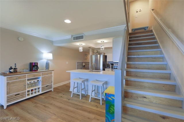 staircase featuring sink, hardwood / wood-style floors, and ornamental molding