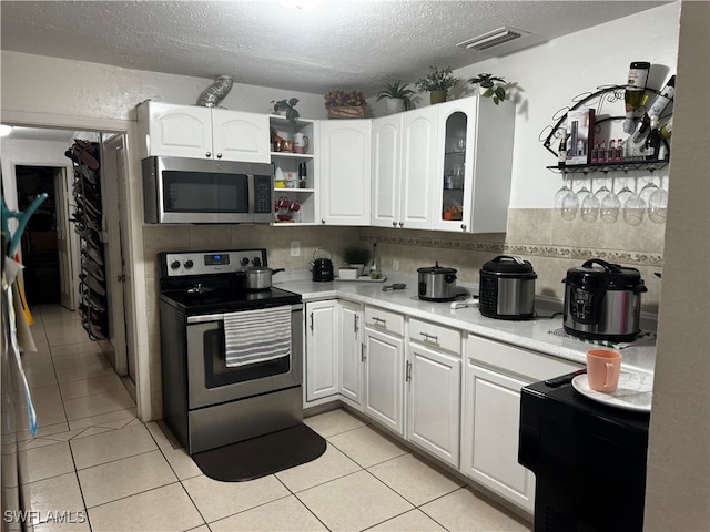 kitchen featuring appliances with stainless steel finishes, white cabinetry, tasteful backsplash, a textured ceiling, and light tile patterned flooring