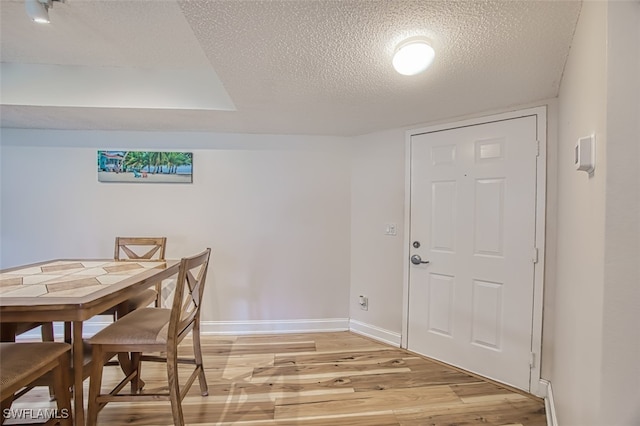 dining room with a textured ceiling and light hardwood / wood-style floors