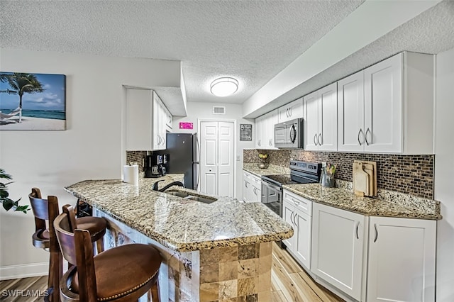 kitchen with white cabinets, kitchen peninsula, sink, and stainless steel appliances