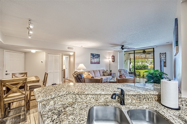 kitchen featuring ceiling fan, hardwood / wood-style floors, track lighting, sink, and a textured ceiling