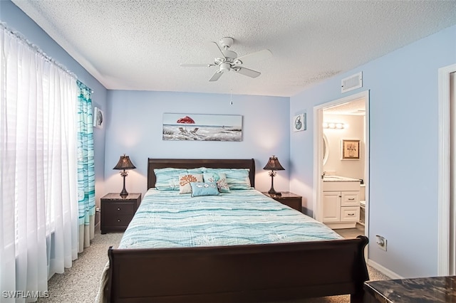 carpeted bedroom with a ceiling fan, connected bathroom, visible vents, and a textured ceiling